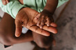 © Drobot Dean - Young african american woman holding her baby's hand at home