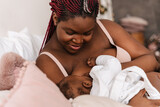 Fototapeta Nowy Jork - Young african american woman breastfeeding her baby in bedroom