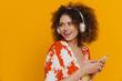 © Drobot Dean - Young beautiful smiling curly woman in headphones holding phone