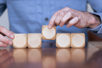 Wall Mural - Close up of a business person arranging large wooden blocks. Business strategy and solutions