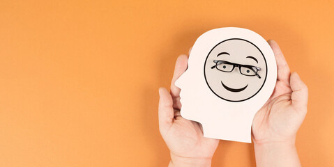 Wall Mural - Holding a head with a happy smiling face, mental health concept, positive mindset, support and evaluation symbol
