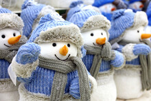 Cute Toy Snowmen In Knitted Clothes And Winter Hats On A Christmas Fair. Festive Shop With Toy Gifts For New Year Celebration