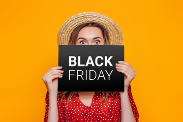 Wall Mural - woman holding paper poster with black friday isolated on an orange studio background