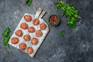 Wall Mural - raw meatballs on wooden board, minced pork meat with spices on a dark background. banner, menu, recipe place for text, top view