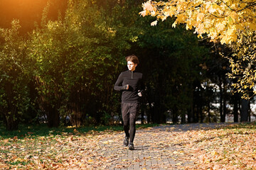 Wall Mural - Man running in park at autumn morning. Healthy lifestyle concept