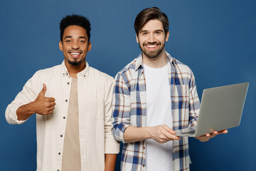 Wall Mural - Young two friends IT men 20s wear white casual shirts together hold use work on laptop pc computer show thumb up like gesture isolated plain dark royal navy blue background. People lifestyle concept.