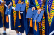 selective focus of african people, in uniform holding hat, colourful black people in traditional wear standing in line outside- graduation concept