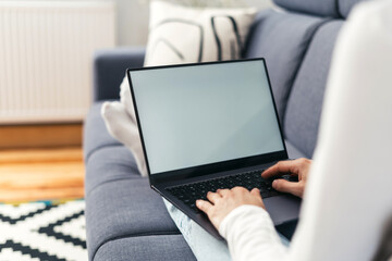 woman with laptop working remote on sofa at home