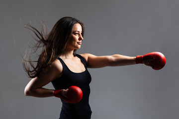 Wall Mural - beautiful girl exercising karate punch against gray background