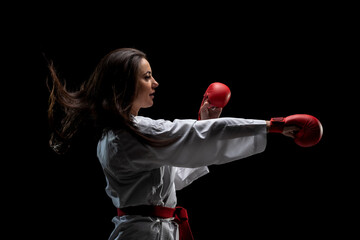 Wall Mural - girl exercising karate punch wearing kimono and red gloves against black background