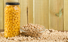 Glass Bowl Of Raw Chickpea Grains And Jar Of Canned Chickpeas On Wooden Background. Concept Of Healthy And Nutritious Food..