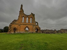 Byland Abbey Ruins With Grass Landscape And Cloudy Gray Sky