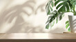 Leinwanddruck Bild - Wooden table counter top with green tropical plant leaf and beautiful sun light and shadow on beige wall for luxury beauty, organic, health, cosmetic, jewelry fashion product display background