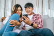 © Johnstocker - Happy Young Asian couple use smartphone enjoy to play game