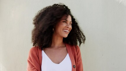 Wall Mural - Beauty, hair and smile with a black woman being happy, playful and cute while standing on a gray background. Portrait of an attractive young female posing and playing with her curls by a wall