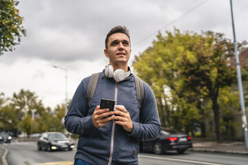 Wall Mural - one young adult man student or tourist use mobile phone while wait bus