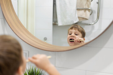 Wall Mural - cute 5 years old boy brushing teeth with bamboo tooth brush in bathroom. Image with selective focus