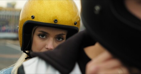 Close-up portrait of a young attractive girl sitting on a motorcycle behind her boyfriend. Couple in love in helmets on a bike