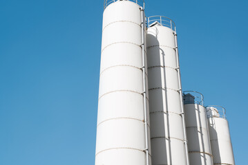 Close-up of a row of white grain storage bins against a clear sky outdoors. Food industry