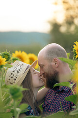 Canvas Print - Young romantic couple in sunflower field in sunset