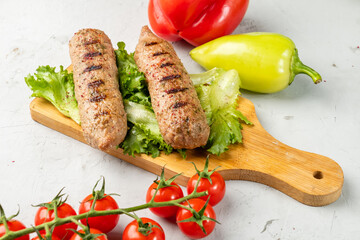 Delicious grilled soy sausages lie on a wooden board next to lettuce and cherry tomatoes. Lula kebab.