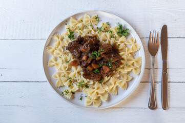 Wall Mural - Brown beef stew with farfalle or bow tie pasta on a plate