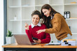© Daenin - Two diverse female designers smile as they work together at a conference room table during a meeting in a modern office. collaboration concept