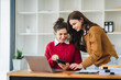 © Daenin - Two diverse female designers smile as they work together at a conference room table during a meeting in a modern office. collaboration concept