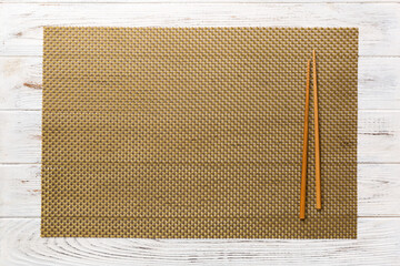 Wall Mural - Two chopsticks and bamboo mat on wooden background. Top view, copy space