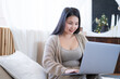© Юля Шевцова - attractive young asian women in cozy clothing using laptop on bed at home, christmas time.