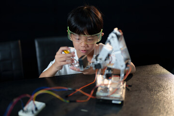 A cute boy constructs metal robot and program it boards microcontrollers on the table STEM education inscription. Programming Mathematics The science Technology DIY workshop at class in the classroom