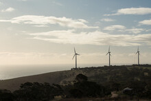 Three Wind Turbines On A Hill Facing The Ocean For Offshore Wind