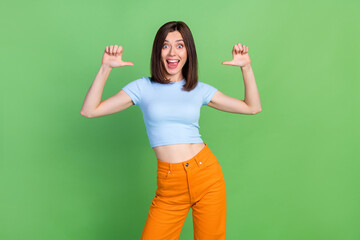 Wall Mural - portrait of positive astonished person direct thumb fingers herself open mouth isolated on green col
