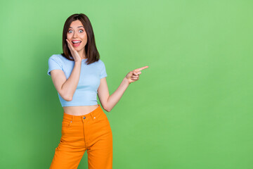 Wall Mural - photo of funny crazy girl hand touch cheek indicate finger empty space isolated on green color backg