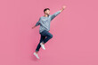 Full size photo of young handsome attractive cool man wear grey pullover jeans stylish sneakers jump fly like superhero worker leader career isolated on pink color background