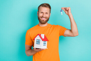 Canvas Print - Portrait of good mood optimistic guy with blond hairdo wear orange t-shirt hand hold small house keys isolated on teal color background