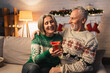 happy middle aged woman holding christmas present near husband in sweater