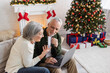 smiling middle aged woman pointing at happy husband and having video call on laptop during christmas