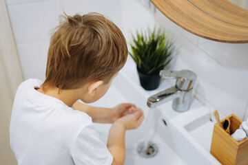 Wall Mural - cute 6 years old boy washing his face over the sink in bathroom. Image with selective focus