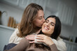 © LIGHTFIELD STUDIOS - Woman kissing cheerful girlfriend with closed eyes at home