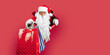 © ZaStock - Santa Claus looking through hole on red paper while holding shopping bags in hand. New Year shopping