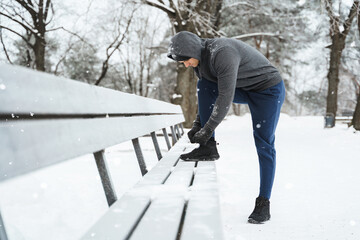 Wall Mural - Jogger man is lacing his shoes during his winter workout