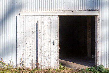 Wall Mural - Full frame abstract texture background of a deteriorating century old barn wall and door, with newer white corrugated steel siding
