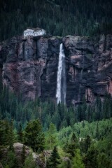 Wall Mural - Scenic vertical shot of a beautiful waterfall in an evergreen forest