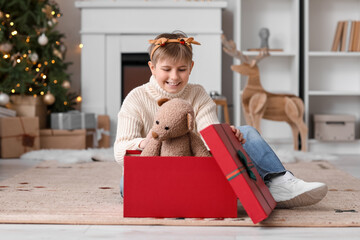 Sticker - Little boy in reindeer horns opening Christmas gift at home