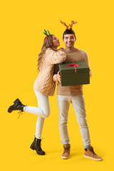 Canvas Print - Young couple in love with Christmas gift on yellow background