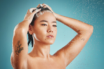 Canvas Print - Asian woman, beauty and shower with water, shampoo and wash against a blue studio background. Female skincare, cleaning and fresh skin, with body wellness, hydration and health with washing hair