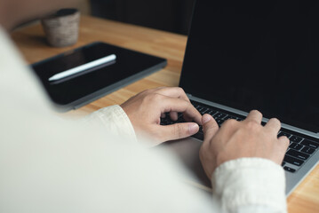 Poster - Business man sitting at table working on laptop computer at office. Man hands typing on laptop keyboard, online working from home, online job, telecommuting, over shoulder view