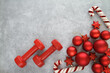 Two red dumbbells, Christmas decorations, baubles and candy cane ornaments. Healthy fitness lifestyle holiday season composition. Gym workout sport training flat lay concept with copy space.