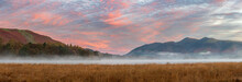 Absolutely Stunning Vibrant Autumn Sunrise Landscape Image Looking From Manesty Park In Lake Distict Towards Sunlit Skiddaw Range With Mit Rolling Across Derwentwater Surface